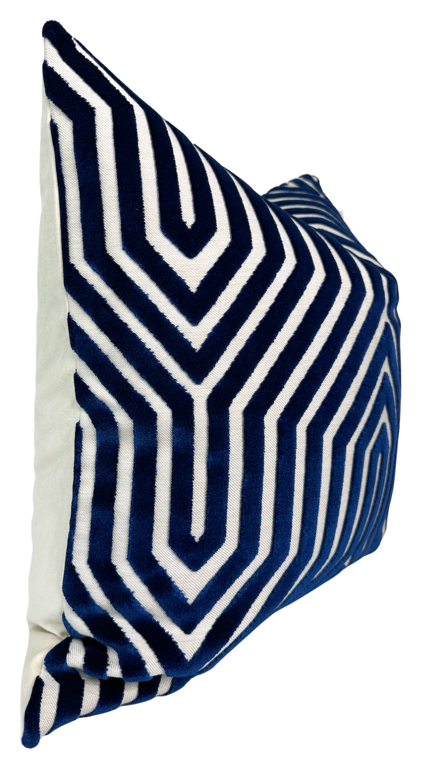 Square navy blue velvet pillow cover with bold white geometric maze-like pattern, shown at an angle against a plain white background.