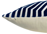 Close-up of a pillow corner featuring a navy blue and white velvet striped top with a hidden white zipper, contrasted against a smooth white bottom fabric.