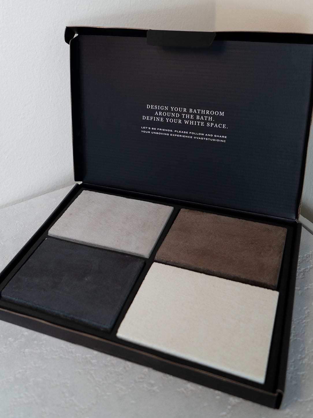 VAST Studio Finish Samples box showing four concrete finish samples in black, gray, bone, and earth brown