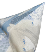 Close-up of a pillow corner featuring a soft blue and cream fabric with delicate willow tree and leaf patterns.