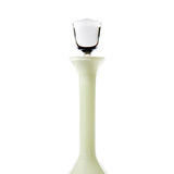 Tall light green glass bottle with a wide flared neck and a clear, faceted stopper on top against a white background.