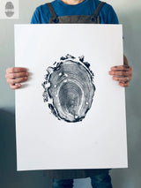 Person holding a white 18x24 print featuring a detailed black tree ring design with irregular bark edges and growth rings at center.