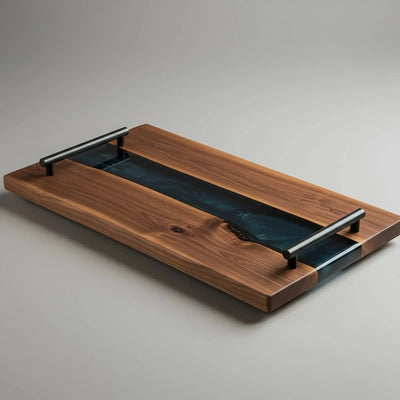 Live edge black walnut charcuterie board with smoky black epoxy resin river and matte black cylindrical handles, handcrafted and sealed with food-safe oil.