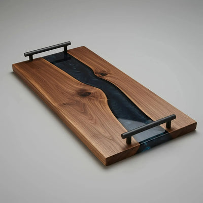 Live edge black walnut charcuterie board with smoky black epoxy resin river and matte black cylindrical handles, handcrafted and sealed with food-safe oil.