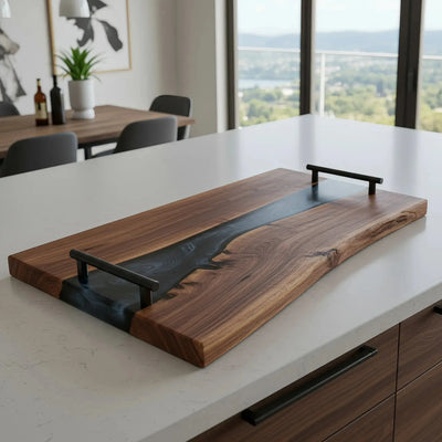 Live edge black walnut charcuterie board with smoky black epoxy resin river and matte black cylindrical handles, handcrafted and sealed with food-safe oil.