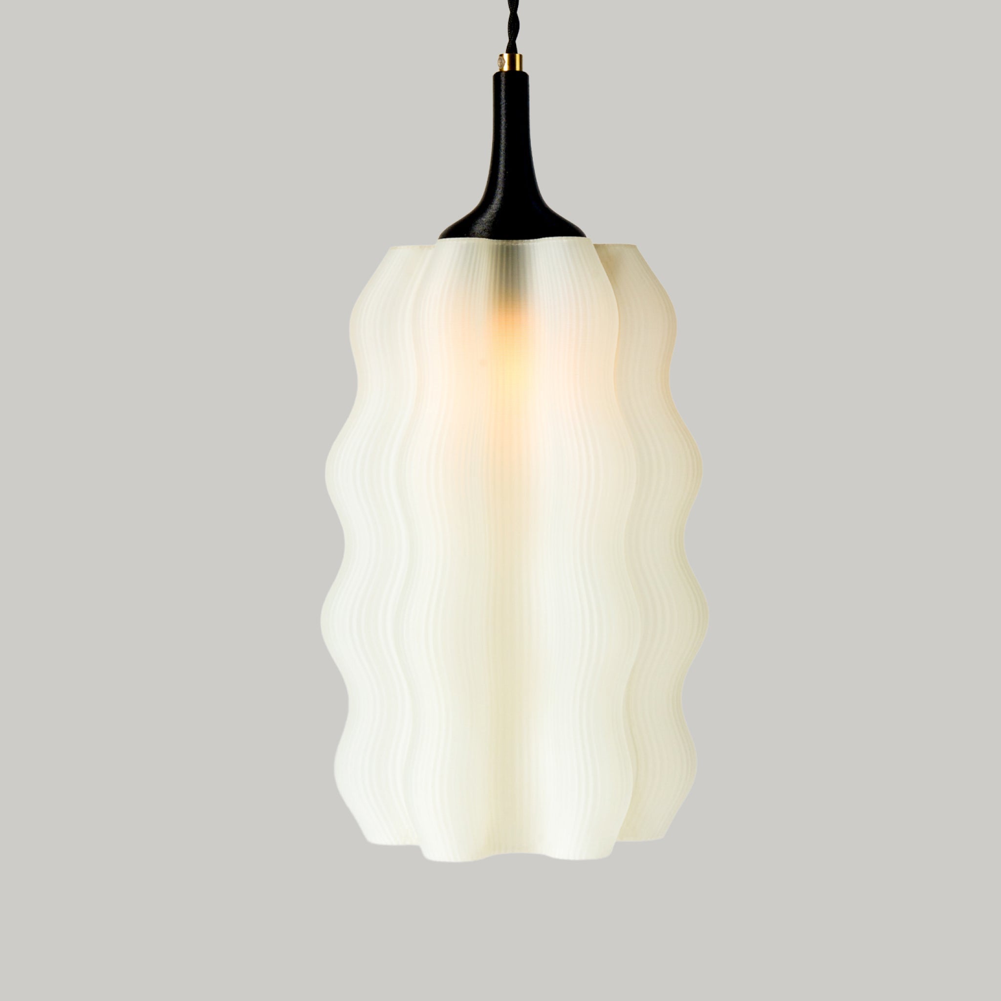 Wavy Pendant lamp hanging, showing its wave-like form and braided cloth cable