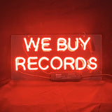 Illuminated 'We Buy Records' neon light sign hanging indoors