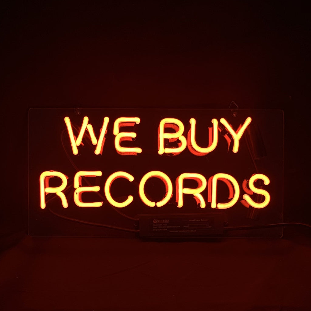 Orange neon light sign with the words 'WE BUY RECORDS' against a dark background