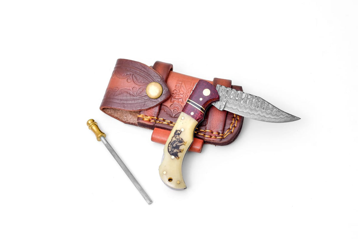 Bear Engraved Damascus Folding Knife with polished bone and wood handle alongside leather sheath and sharpening rod