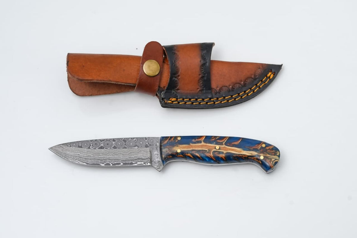 Handmade Damascus Steel Knife with Blue Pine Cone Handle & Leather Sheath TK-427 lying on a wood surface