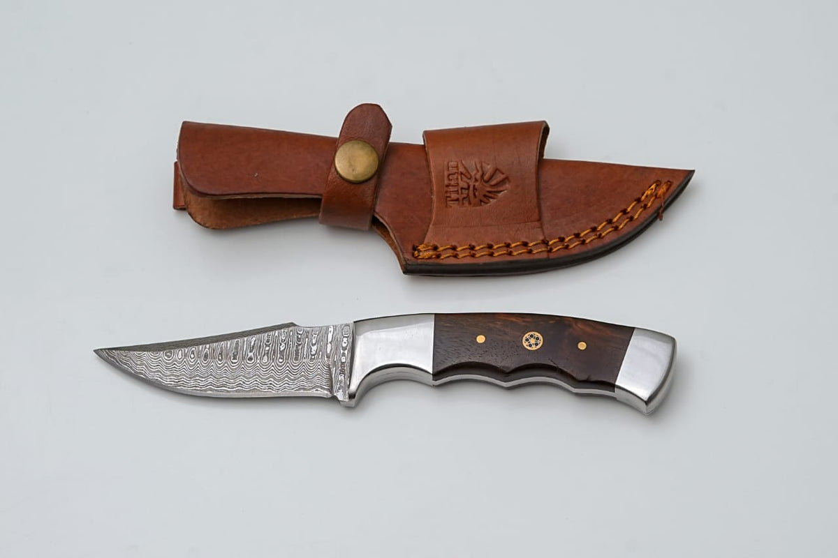Handmade Damascus Steel Knife with Wenge Wood Handle and embossed leather sheath laid on stone surface