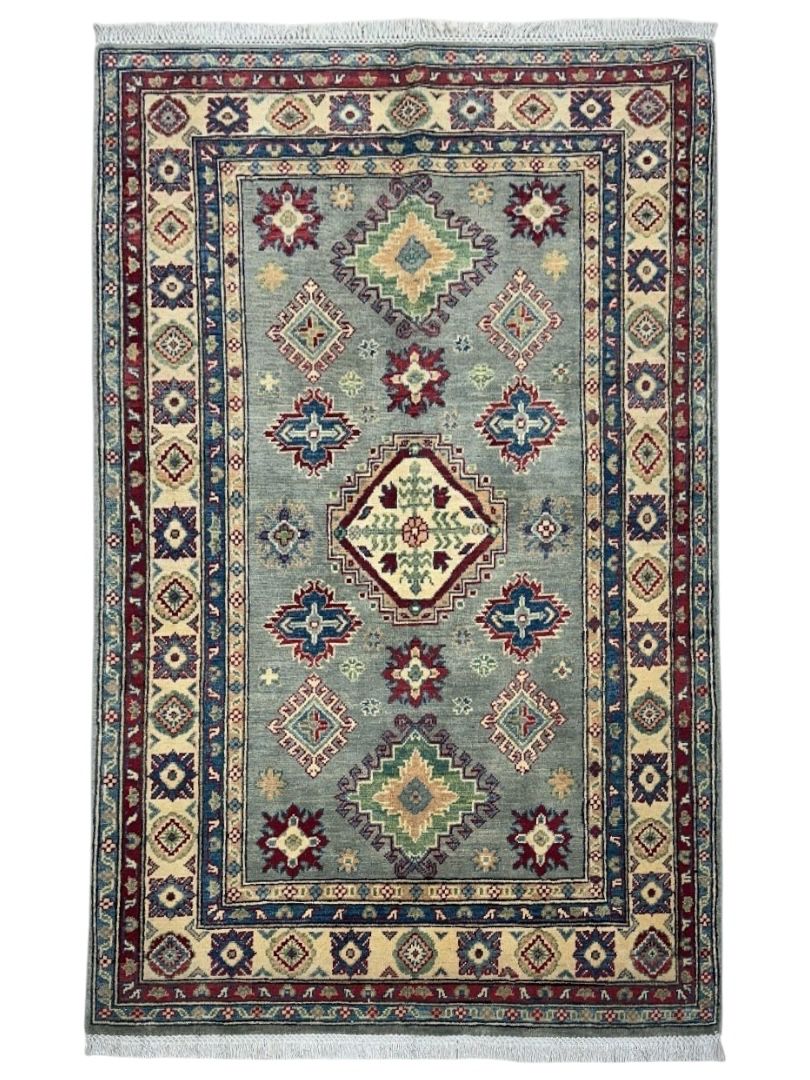 Hand-knotted Afghani Kazak wool rug in beige and red tones laid in a room