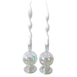 Pair of tall white candles with a twisted spiral design, each held in a clear iridescent glass holder with a rounded base.