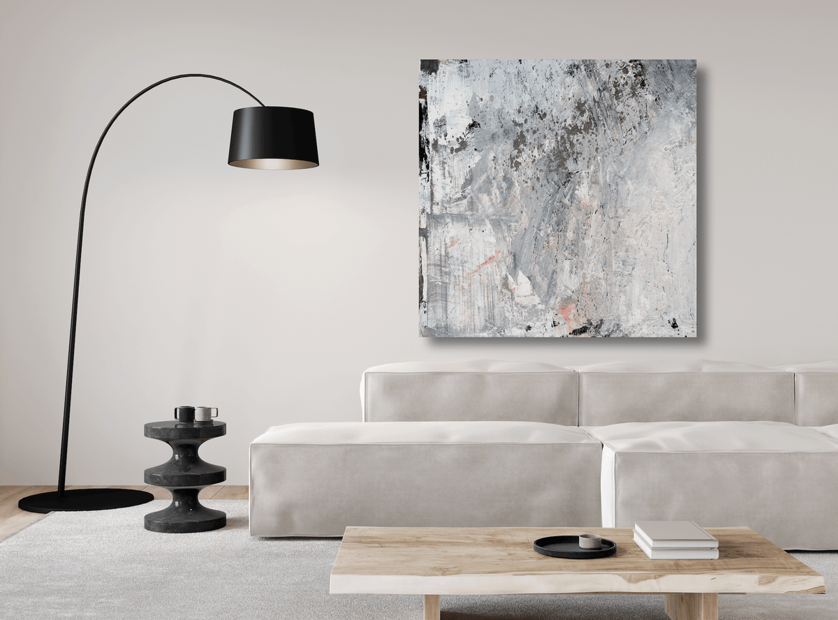 Abstract gray, white, and black textured canvas print titled White Code hangs on a light beige wall above a cream sofa and a black arc floor lamp.