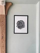 Black and white framed print of an oak tree cross-section showing rings, mounted on a light gray wall next to a wooden architectural bracket