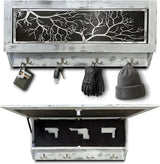 Rectangular wall-mounted wooden box with a whitewashed finish and a black panel featuring white tree branches, with four hooks holding keys, gloves, and a hat; the box opens to reveal a hidden compartment with three gun-shaped cut