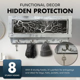 Wall-mounted wooden gun concealment decor with a tree branch cutout design and eight hooks holding keys, gloves, and a hat, shown in a gray distressed finish.