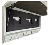 White distressed wood wall-mounted gun concealment decor with three metal hooks below and black foam slots inside for securing firearms.
