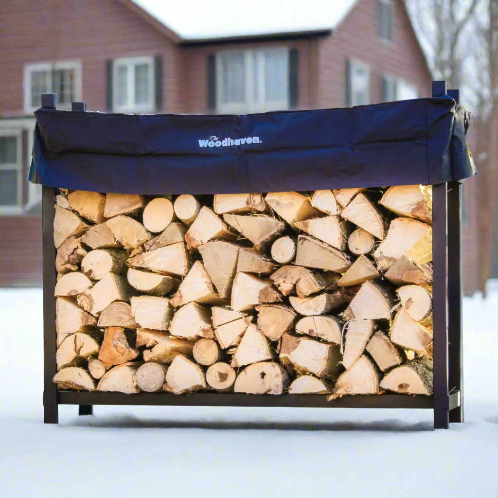 The Woodhaven 5 ft Firewood Rack in black showing stacked firewood on a patio
