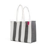 Black and white striped woven tote bag with two white rope handles and a small pink tag near the top edge, shown angled on a white background.