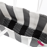 Close-up of black and white woven fabric with a zebra stripe pattern forming the interior of a tote bag, with white handles partially visible.
