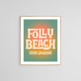 Framed modern art print with retro-style text 'Folly Beach South Carolina' in cream and peach on a green and orange gradient background.