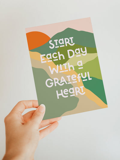 Grateful Heart Blank Note Card laying on a pink surface next to an envelope and a pen