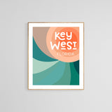 Framed modern art print with abstract swirling shapes in teal, peach, and coral, featuring stylized text reading 'Key West Florida' at the top right.