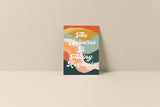 Note card with colorful abstract waves in orange, teal, green, pink, and cream, displaying white cursive text reading 'The Universe Is Taking Requests'.