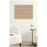 Rectangular beige pinboard with evenly spaced red botanical block print patterns, framed in light wood, hanging on a white wall above a small brass table between two cream upholstered chairs.