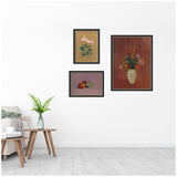 Three framed art prints on a white wall featuring a pink cyclamen on golden background, fruit still life with peach and grapes on lavender, and multicolored bouquet in a light vase on reddish background.