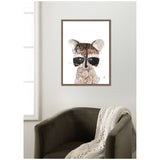 Framed wall art print of a stylized raccoon with black eye patches and textured brown fur, hanging above an olive-green armchair draped with a cream knit blanket.