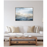 Abstract horizontal canvas with muted blue, gray, and beige tones evoking a serene oceanic atmosphere, framed in dark wood, hanging above a neutral beige sofa.