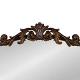 Top portion of an arch mirror with a dark wood frame featuring ornate carved acanthus leaves and scroll details in a traditional style.