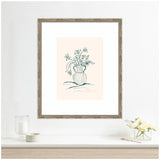 Framed minimalist line drawing of flowers in a striped vase with green outlines on pale pink background, displayed on a white wall above a table with a candle and flowers.