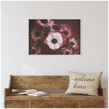 Framed canvas of deep pink and white anemone flowers with dark centers hanging above a wooden bench with a "welcome home" pillow and an open book.