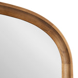 Close-up of the top corner of an arch-shaped wall mirror with a smooth, warm-toned wooden frame featuring natural grain variations.