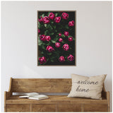 Framed canvas showing dark pink tulip buds with green leaves on a black background, hanging above a wooden bench with a 'welcome home' pillow and open book.