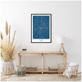 Framed deep blue map of Atlanta on white wall above rustic wooden console table with wicker baskets and natural pampas grass arrangement in a bright, minimalist room.