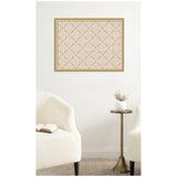 Framed beige pinboard with a green lattice pattern composed of small dots and crosses, hung above a brass side table with a small white vase and dried flowers, between two white upholstered chairs.