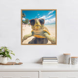 Framed photo of a turtle wearing red sunglasses on a sunny beach with blue sky and ocean, hanging above a white desk with plants and books.