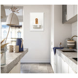 Modern kitchen with light gray stone countertops, white cabinetry, and a framed canvas of a golden doodle sitting in a white bathtub on a white wall.