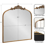 Arched rectangular mirror with antique gold frame featuring an ornate carved crown detail at the top center, shown with measurements and D-ring hanging hardware on the back.
