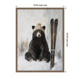 Painting of a black bear sitting in snow wearing a beige knitted hat with pom-pom, next to a pair of upright brown skis, framed in simple wood.