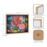 Framed bright coral underwater print with red, pink, yellow, and blue coral shapes on a dark background in a natural oak wood gallery frame.