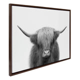 Black and white portrait of a Highland cow with long shaggy hair covering its eyes, displayed in a dark wooden frame with a white background.