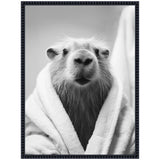 Close-up black and white photo of a capybara wrapped in a soft towel, with its head centered and fur slightly wet, framed in a textured dark border.