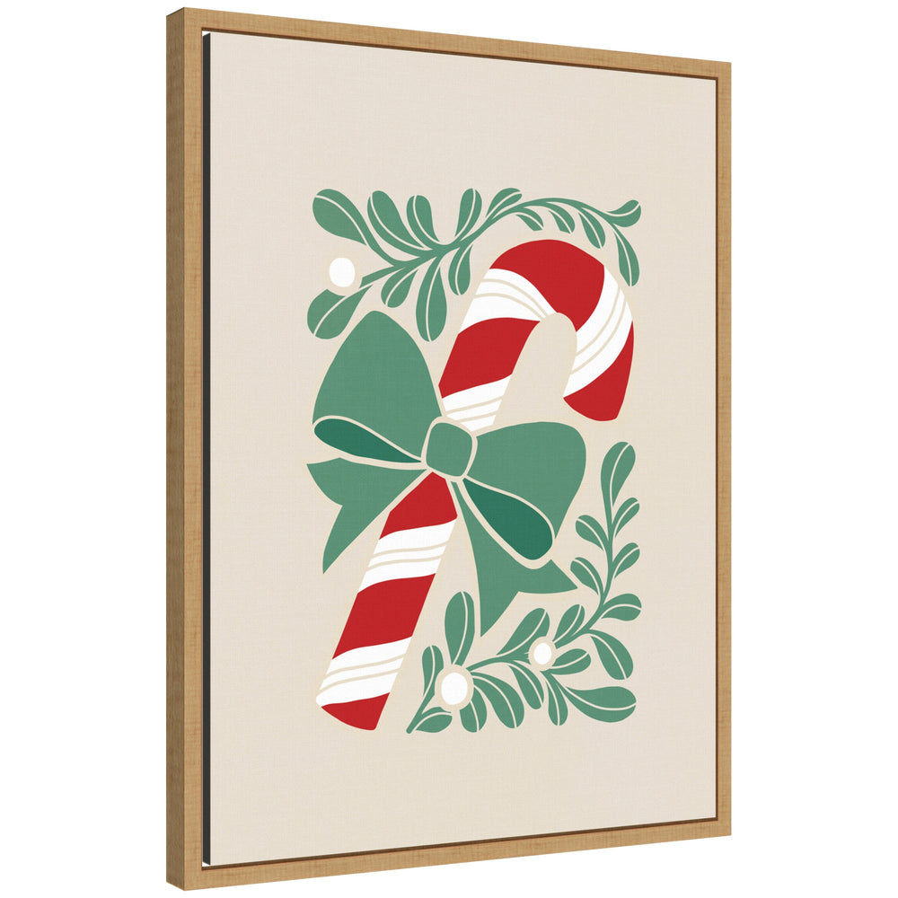 Framed canvas art showing a red and white candy cane with a green bow, surrounded by stylized green leaves and mistletoe berries