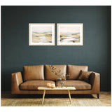 Two framed landscape watercolor prints with soft greens and beiges hung side by side above a brown leather sofa with a wooden coffee table in front.