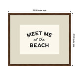 Framed wall art with dark brown wooden frame featuring black text 'MEET ME at the BEACH' on a light beige background, measuring 25 by 21 inches.